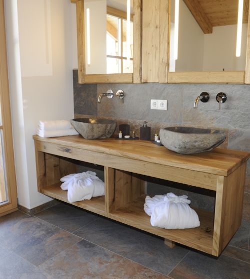 Modernes Badezimmer mit Holztisch, Steinwaschbecken, Spiegelschrank und Balkon.